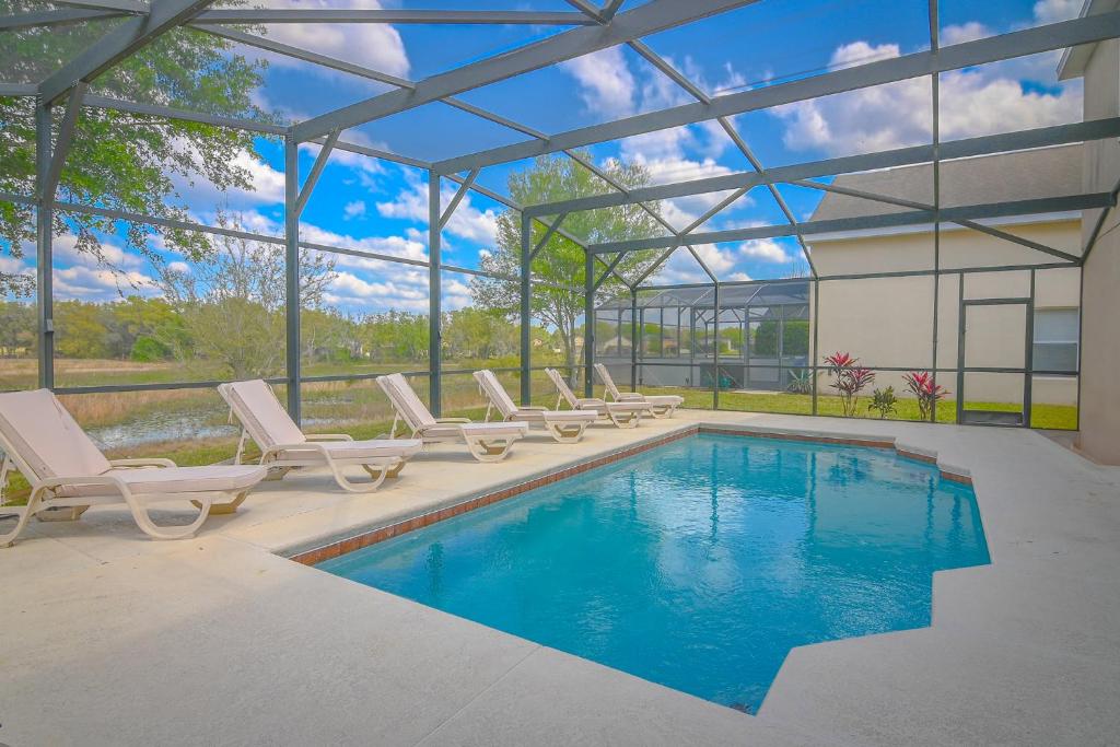 ein Swimmingpool mit Liegestühlen neben einem Gebäude in der Unterkunft The Andalusian Escape Near Disney in Davenport