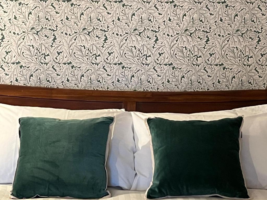 Granby Cottage, Peak District National Park في تيديسويل: اثنين من الوسائد الخضراء يجلس على رأس سرير