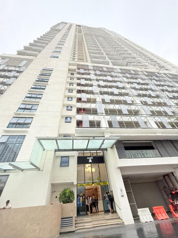 a tall white building with people standing in the doorway at Colony Service Suites Kuala Lumpur in Kuala Lumpur