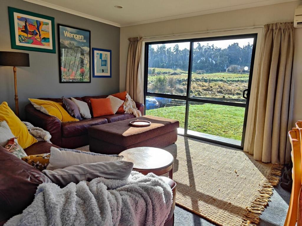 Una sala de estar con un sofá y una ventana grande. en Ohakune Peak Retreat Unit 2, en Ohakune