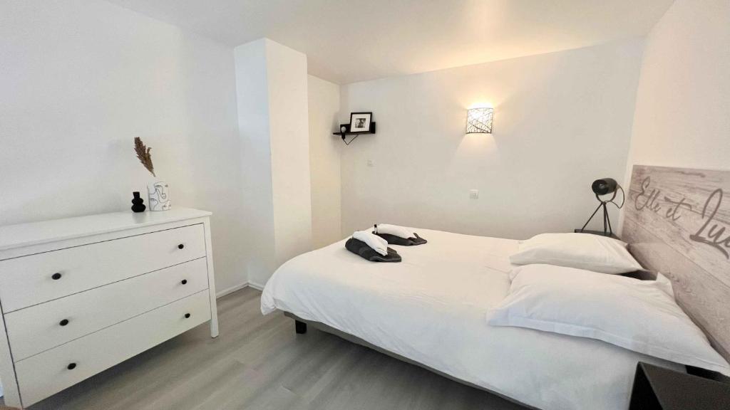 - une chambre avec un lit blanc et une commode blanche dans l'établissement L'atelier proche Paris Marne la Vallée avec Parking Gratuit, à Bussy-Saint-Georges