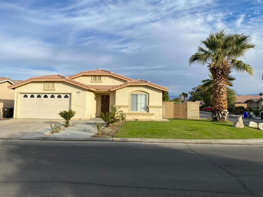 a house on a street with a palm tree at Walking Distance to Stagecoach in Indio