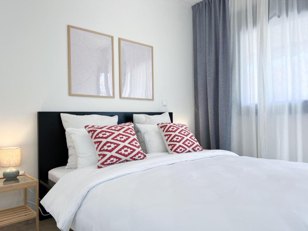 een slaapkamer met een bed met rode en witte kussens bij Near Beach and Easy Parking - By Solstad in Kavala