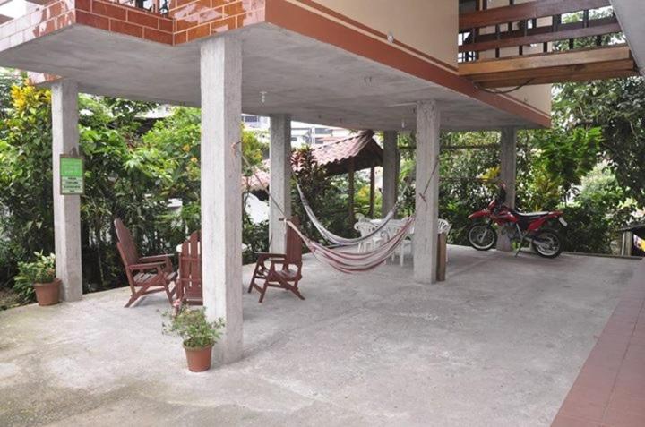 a porch with a hammock and a house at A Welcome Break Hostal in Tena