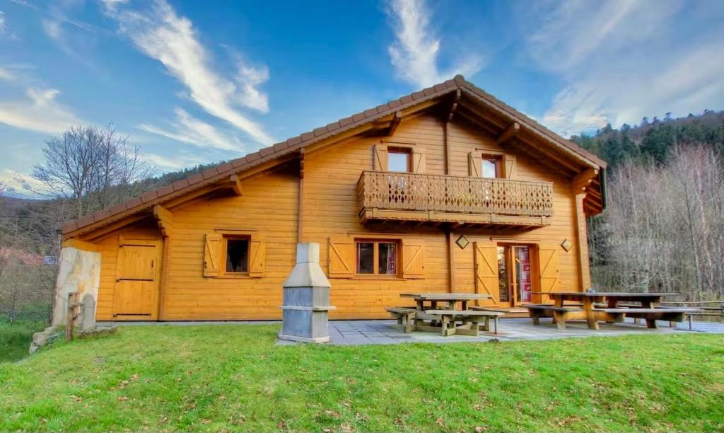 eine Blockhütte mit Picknicktischen davor in der Unterkunft Le Murmure du Ruisseau, 4 étoiles avec sauna et terrasse in La Bresse