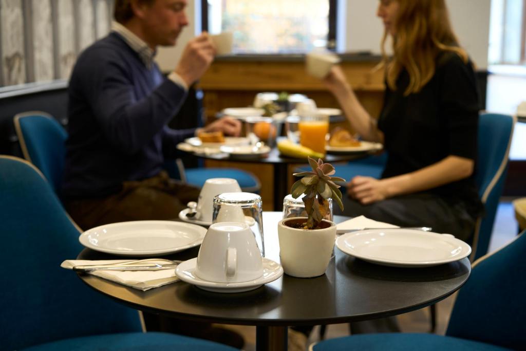 a man and a woman sitting at a table with food at Hotel Do Pozzi in Venice