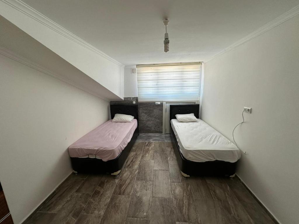 Habitación pequeña con 2 camas y suelo de madera. en VİLLAASUR inst-mariyatourdidim, en Didim