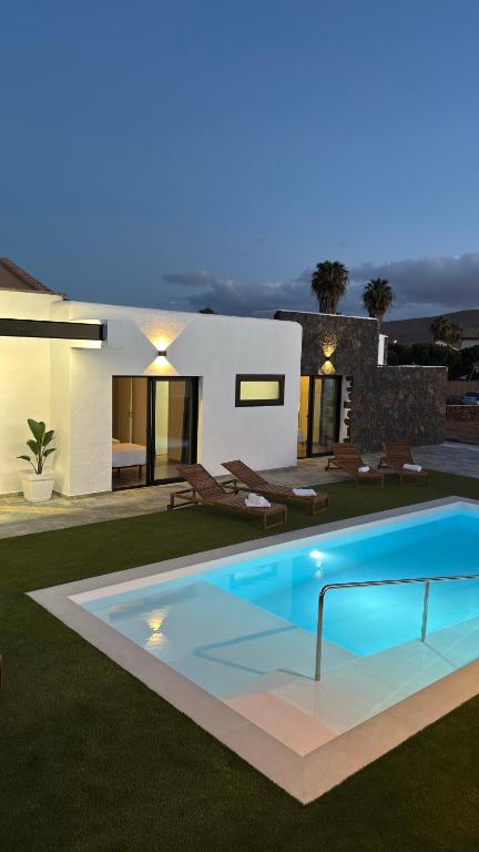 a villa with a swimming pool in front of a house at Casa El Cachorro in La Oliva