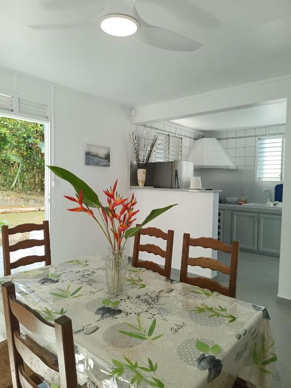 a dining room table with a vase of flowers on it at Belle location vue sur mer in Deshaies