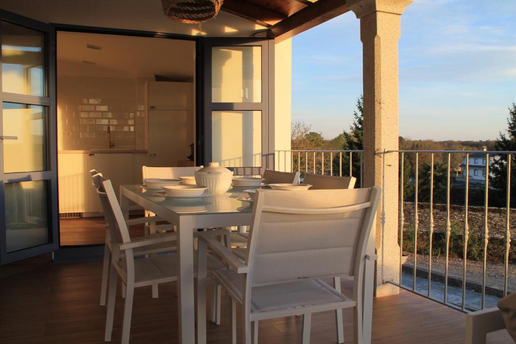a white dining table and chairs on a balcony at Hotel Apartamentos Casas da Fortaleza in Lugo