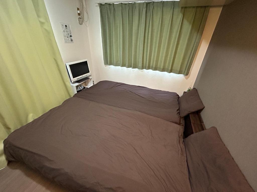 ein kleines Schlafzimmer mit einem Bett und einem Fenster in der Unterkunft Guest House Yakuin INN in Fukuoka