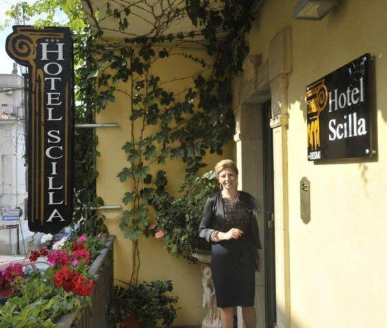 a woman standing outside of a hotel sale sign at Hotel Scilla in Scilla
