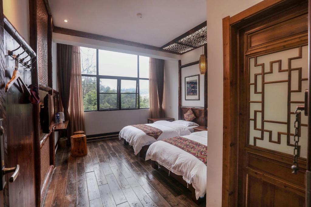 two beds in a room with two windows at 张家界畔山驿栈 in Zhangjiajie