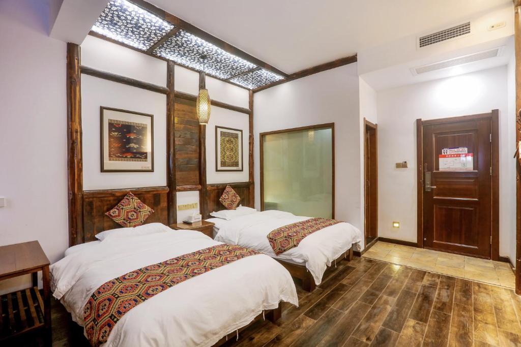 two beds in a room with white walls and wooden floors at 张家界畔山驿栈 in Zhangjiajie