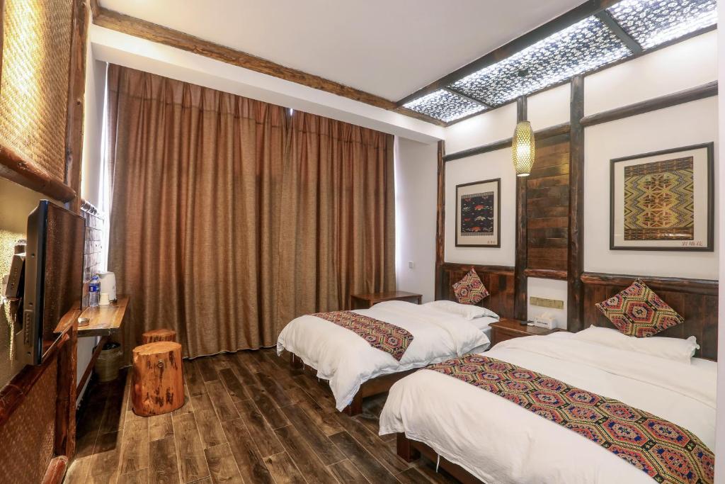 a hotel room with two beds and a television at 张家界畔山驿栈 in Zhangjiajie