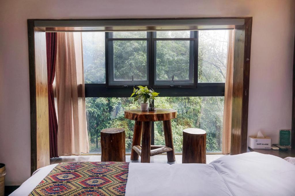 a bedroom with a window with a bed and a table at 张家界畔山驿栈 in Zhangjiajie