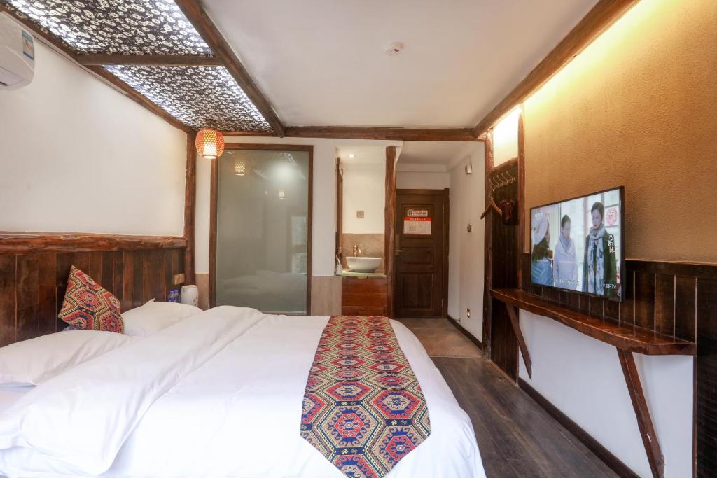a bedroom with a white bed and a bathroom at 张家界畔山驿栈 in Zhangjiajie