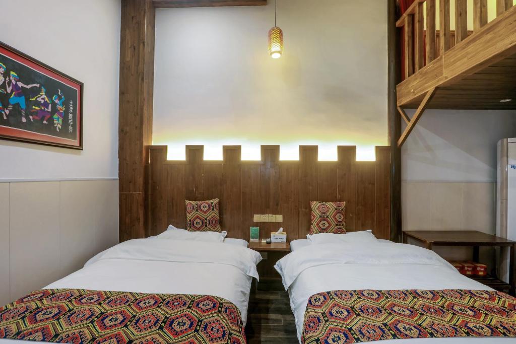 two beds sitting next to each other in a room at 张家界畔山驿栈 in Zhangjiajie