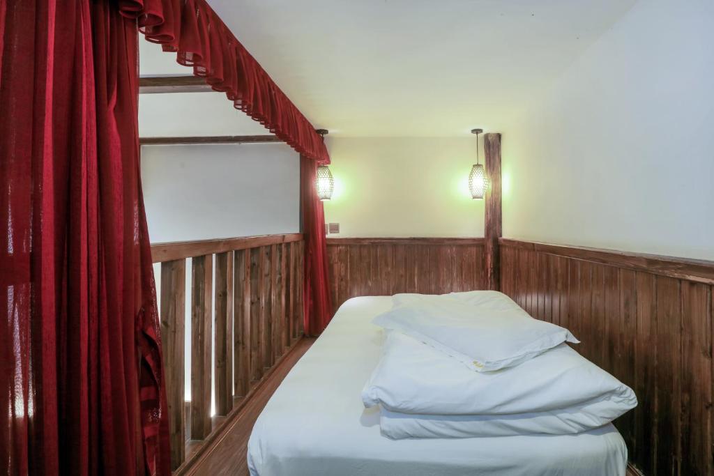a small bed in a room with a red curtain at 张家界畔山驿栈 in Zhangjiajie