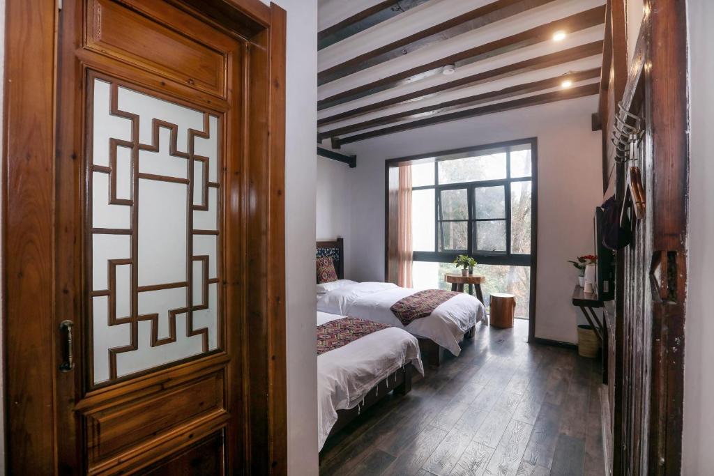a bedroom with two beds and a door at 张家界畔山驿栈 in Zhangjiajie