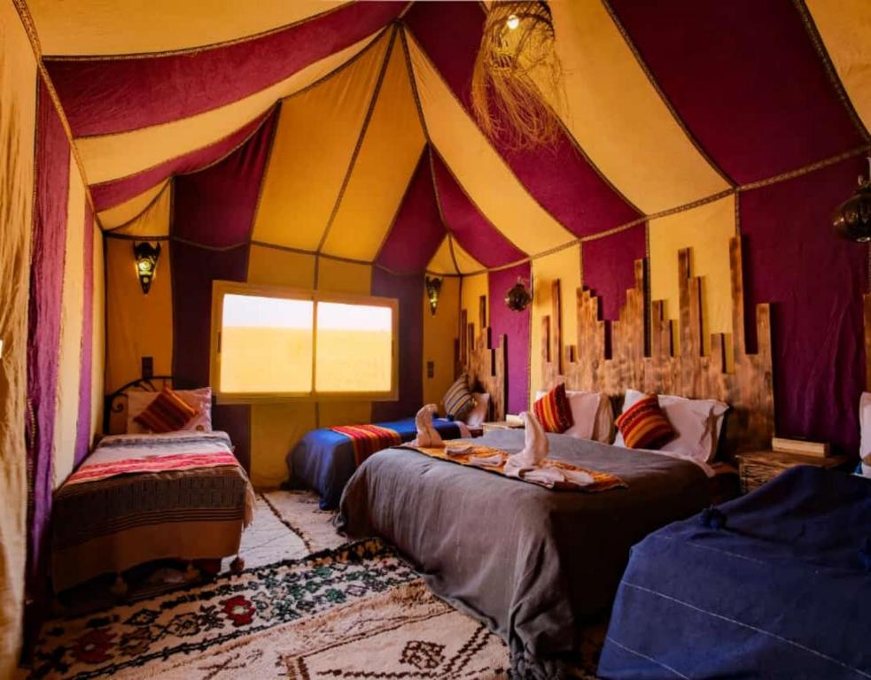 una habitación con dos camas en una carpa de circo en Desert Lodge Luxury Camp, en Merzouga