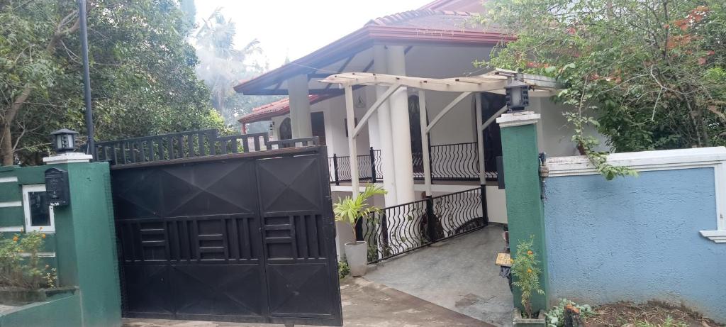 a house with a black gate and a blue fence at Johans Villa Kandy in Kandy