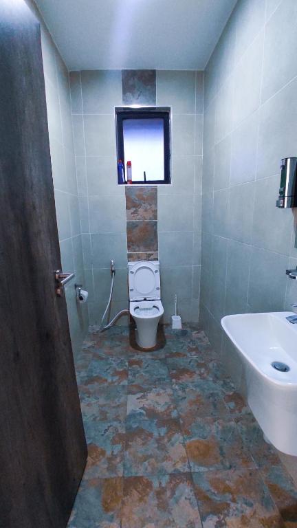 a bathroom with a toilet and a sink and a window at Serene Hills Home in Nairobi