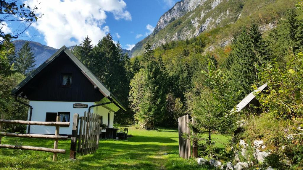 a small house in the mountains with a fence at Počitniška hiša Ukanc in Bohinj