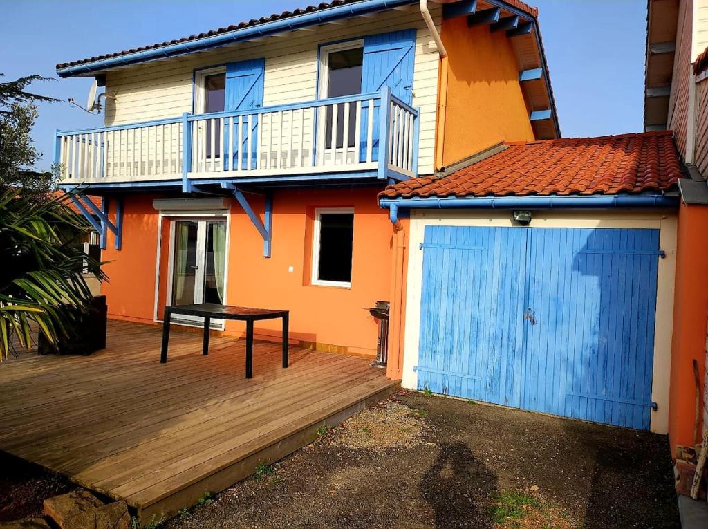 a house with a blue door and a wooden deck at Villa avec piscine L'Abris Côtier in Mimizan