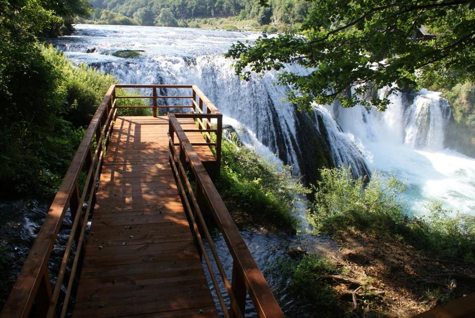 a wooden bridge over a river with a waterfall at Apartments Hills in Ćukovi