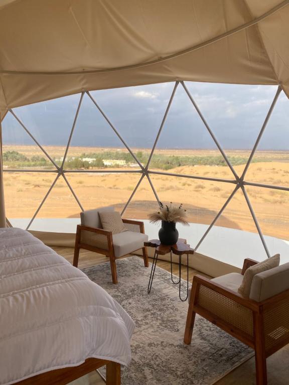 a bedroom with a bed and a view of the desert at Aman dome desert in Ḩawīyah