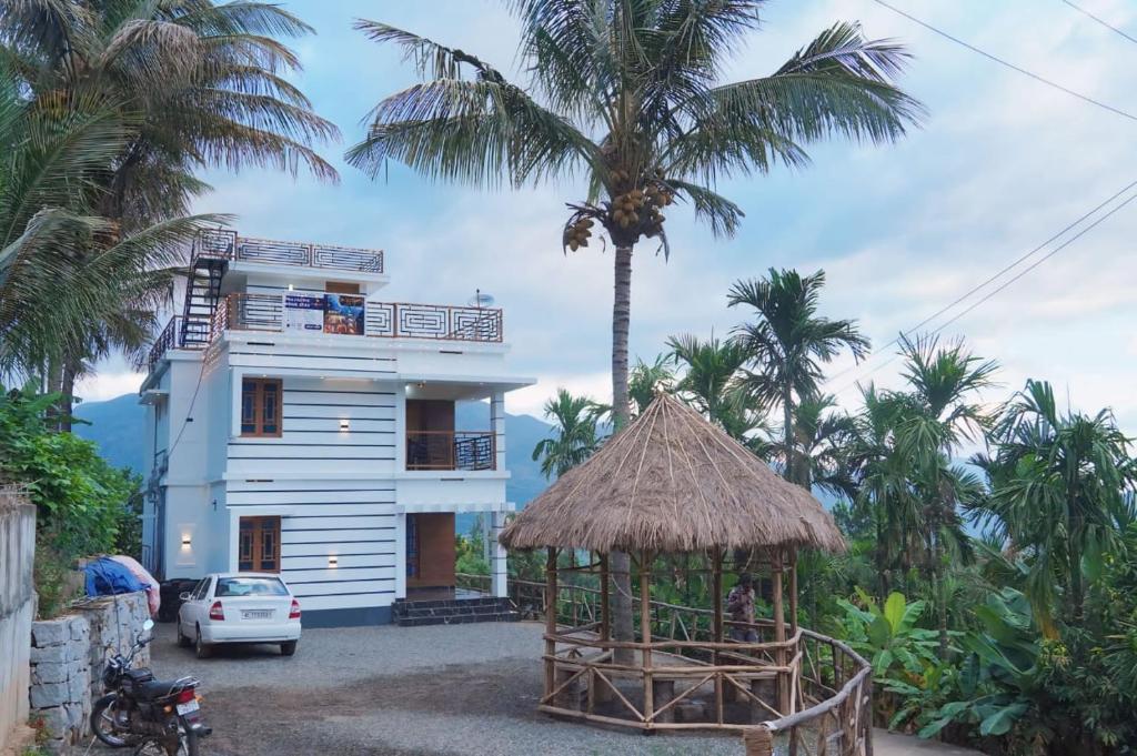 KanthalloorPalm View Kanthalloor的一座棕榈树白色的房子和一座建筑