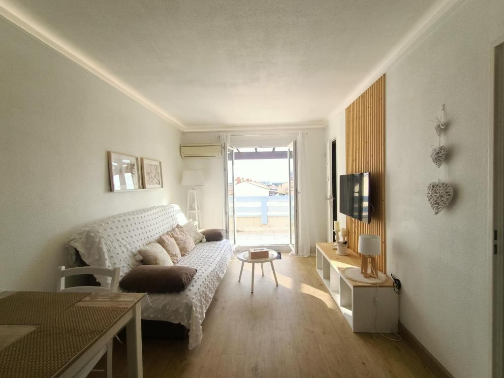 un salon avec un canapé blanc et une télévision dans l'établissement Beau T2 Climatisé avec Terrasse et Parking - FR-1-799-49, au Barcarès