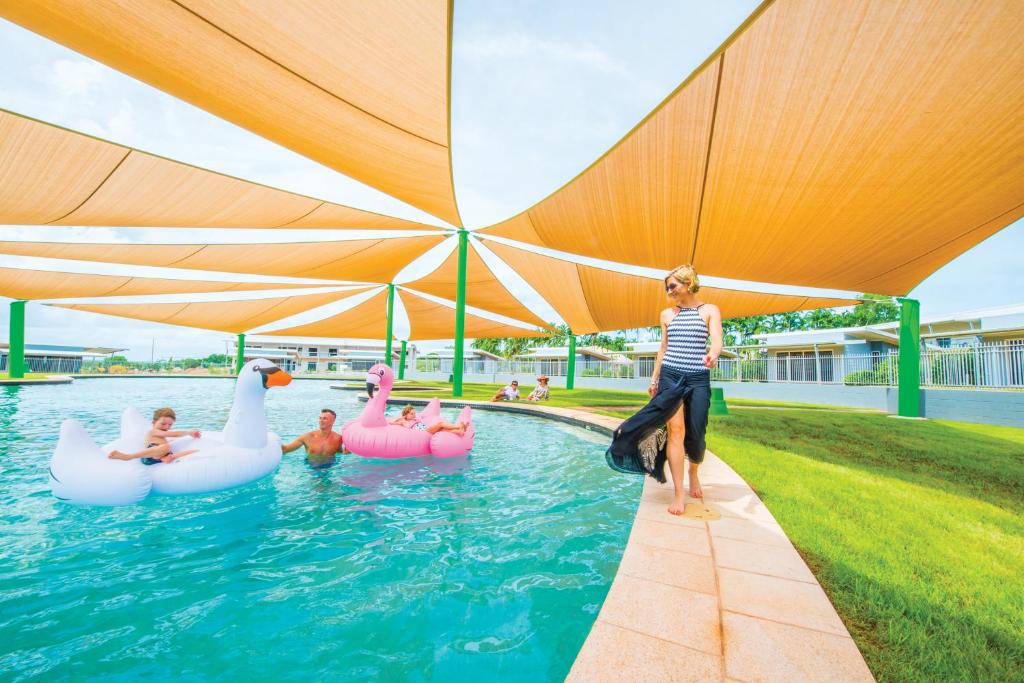 a woman is playing in a pool with inflatable swans at Club Tropical Resort Darwin in Darwin