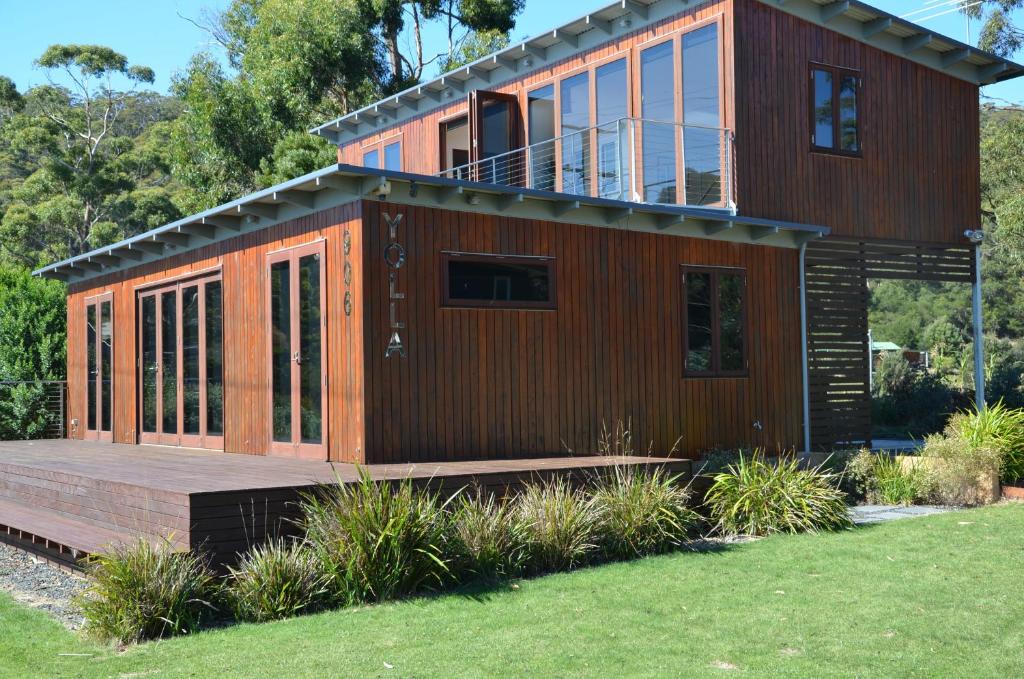 een groot houten huis met een terras in een tuin bij Yolla Beach House in Adventure Bay