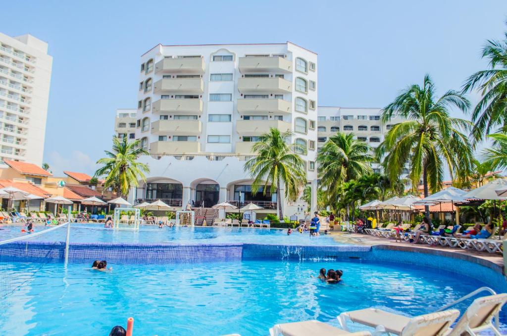 ein Pool in einem Resort mit Menschen im Wasser in der Unterkunft ENNA INN IXTAPA DEPARTAMENTOS ViSTA AL MAR in Ixtapa