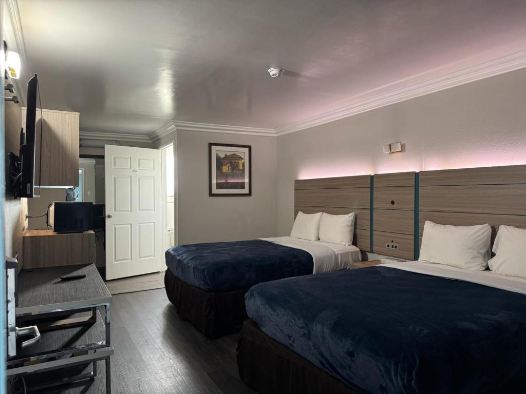 um quarto de hotel com duas camas e uma televisão em Rodeway Inn em Ventura