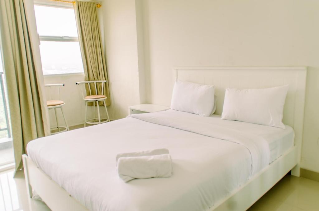 a white bed in a room with a window at Comfort and Homey Studio at Parkland Avenue Apartment By Travelio in Tangerang