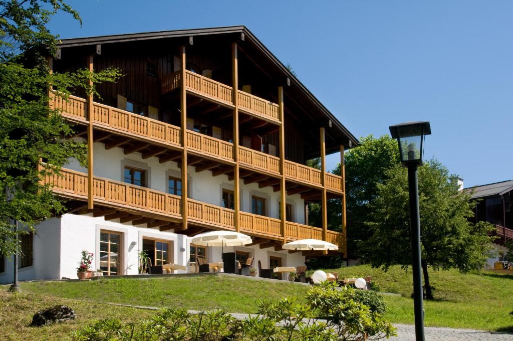 a large building with a balcony with umbrellas at Alpenvilla Berchtesgaden Hotel Garni in Berchtesgaden