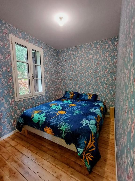 une chambre avec un lit avec une couette bleue et une fenêtre dans l'établissement Maison Normande en lisière de la forêt, à Bernay