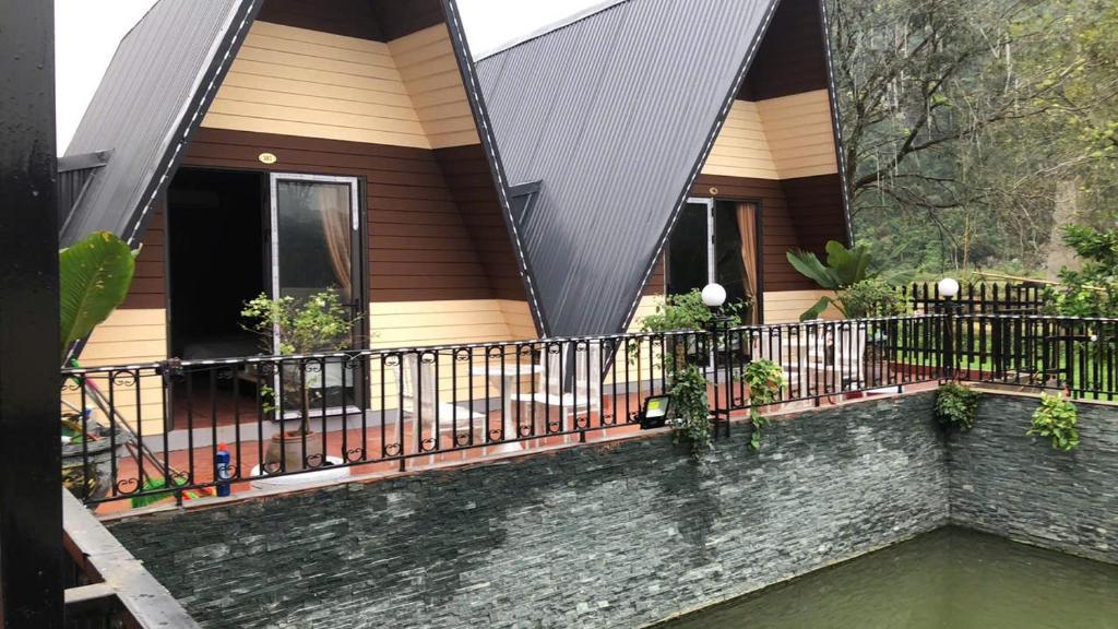 a house with a fence and water in front of it at Aroma Viet Hai Village Homestay in Khê Bao