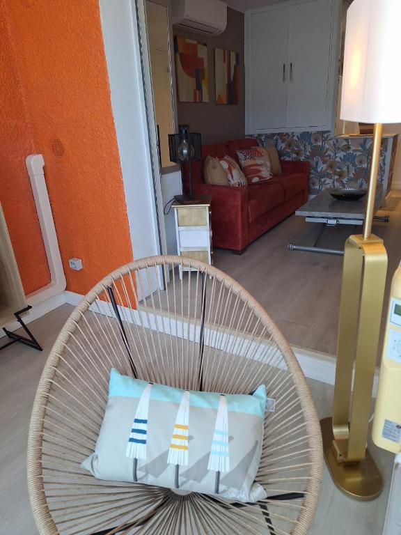 - une chaise en osier avec un oreiller dans le salon dans l'établissement Mimilou Eleuthera 500 metres du centre naturiste, au Cap d'Agde