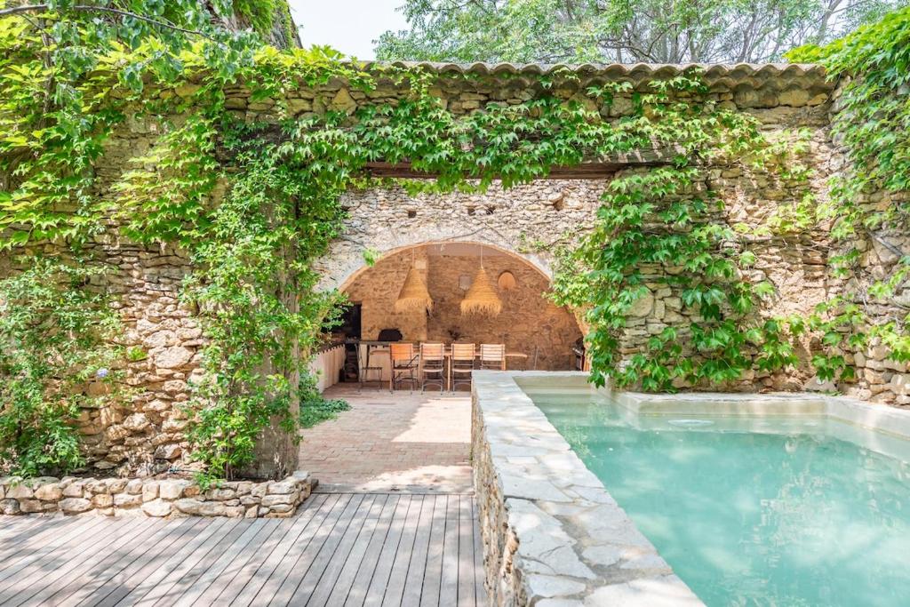 un mur en pierre avec une arche et une piscine dans l'établissement Mas de 190m2 Climatisé avec Piscine et Cuisine d'été - 10 pers, à La Fare-les-Oliviers