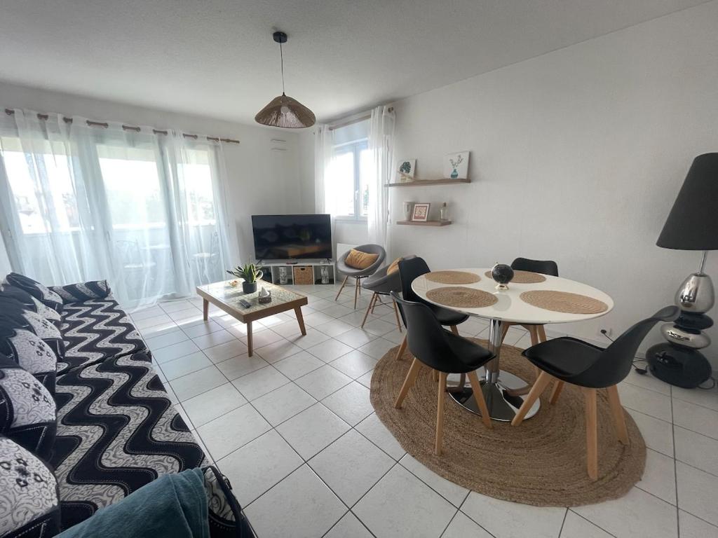 un salon avec un canapé, une table et des chaises dans l'établissement Joli appartement vue Pyrénées, à Pau