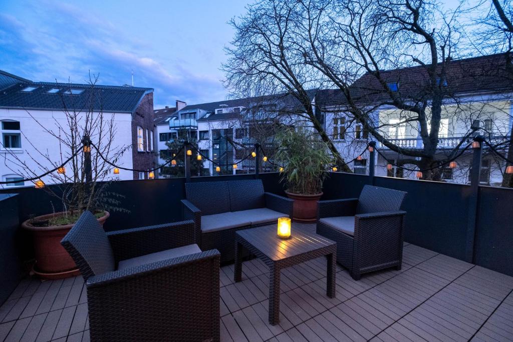 un patio con sillas y una mesa con una vela. en Bismarck Home - Central and Relaxing with Rooftop Terrace in Essen, en Essen