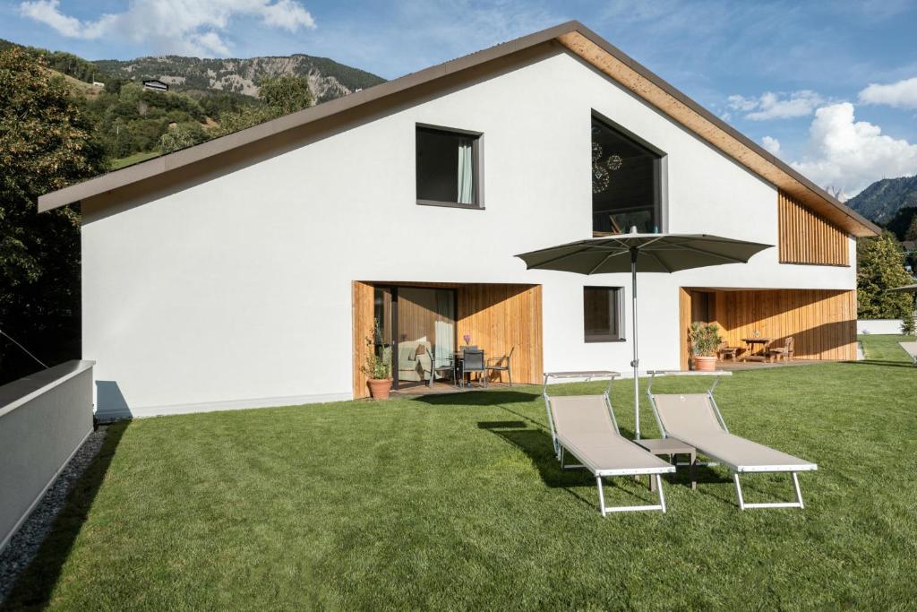 a white house with two chairs and an umbrella at Chalet Samont in Laion