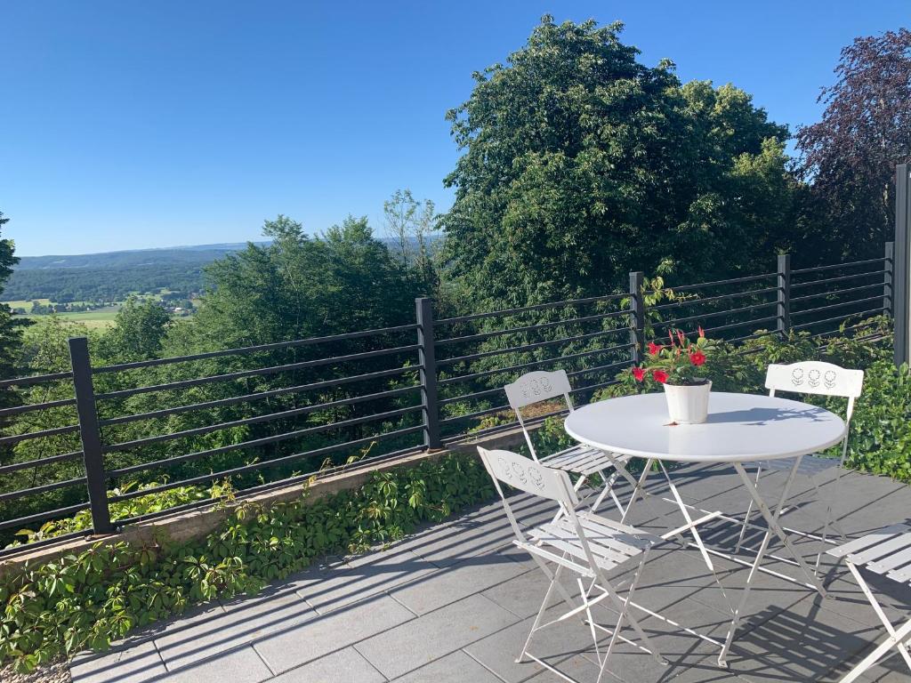 a table and chairs on a patio with a fence at la Maison du fort de Fontain maison cosy vue magnifique sur les Montagnes du Jura in Fontain