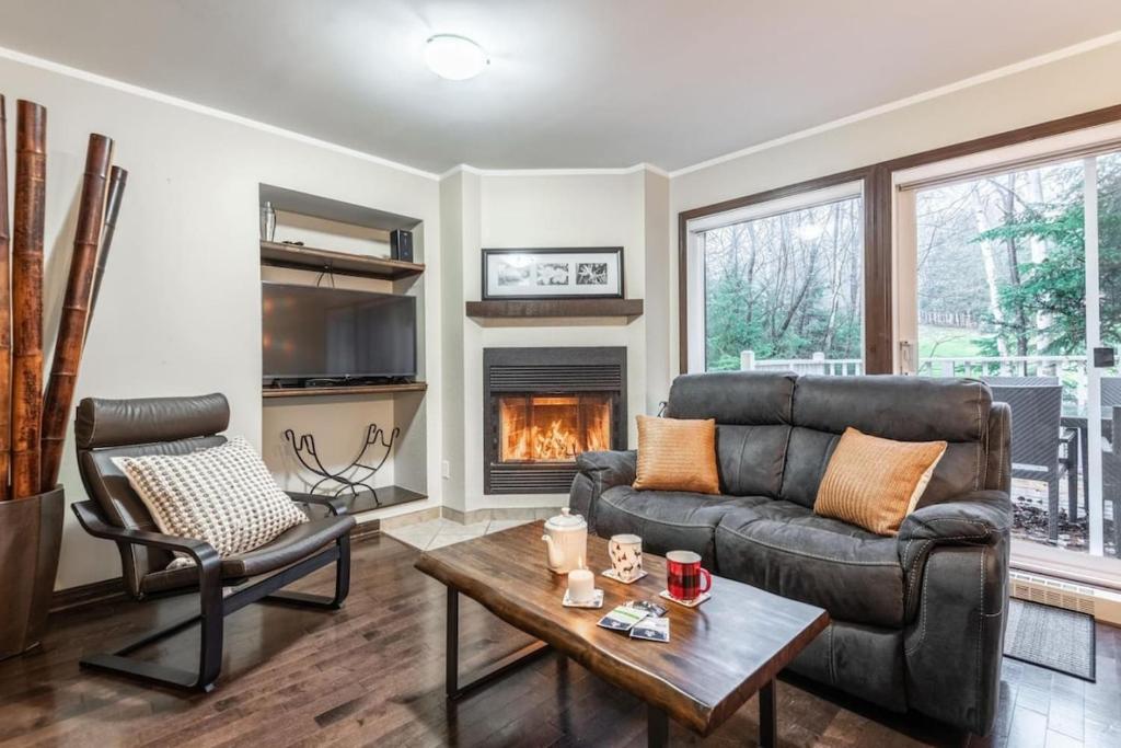 a living room with a couch and a fireplace at Townhouse With Free Shuttle To Tremblant Resort in Mont-Tremblant