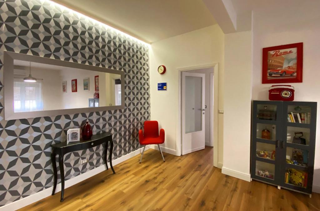 un soggiorno con una sedia rossa e una parete di Torre Maura Apartment a Roma
