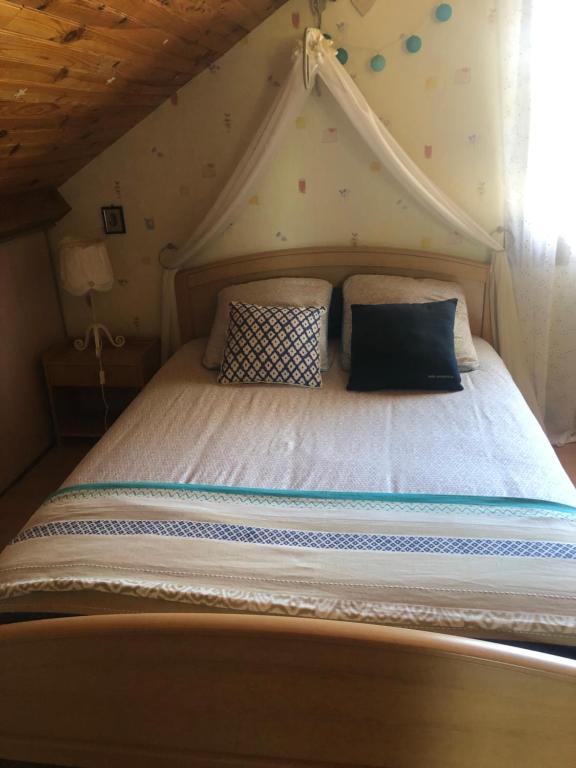 - une chambre avec un lit à baldaquin et des oreillers dans l'établissement Une ou deux Chambres Spacieuses, à Combles-en-Barrois